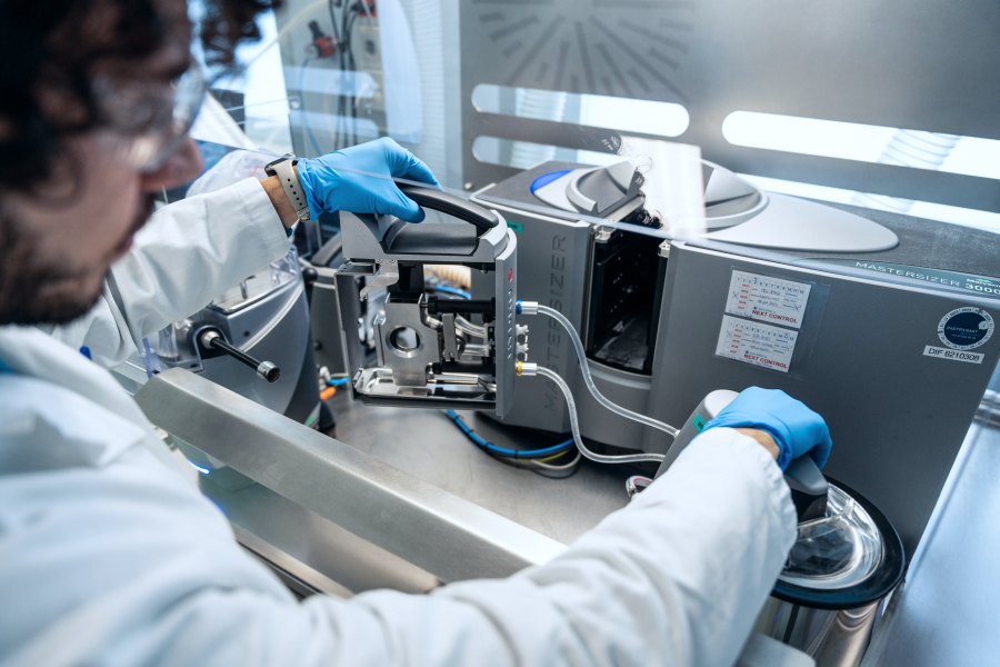 A Malvern Mastersizer - laser diffraction - being operated by a researcher wearing a lab coat and eye protection inside a pharmaceutical GMP analytical laboratory.